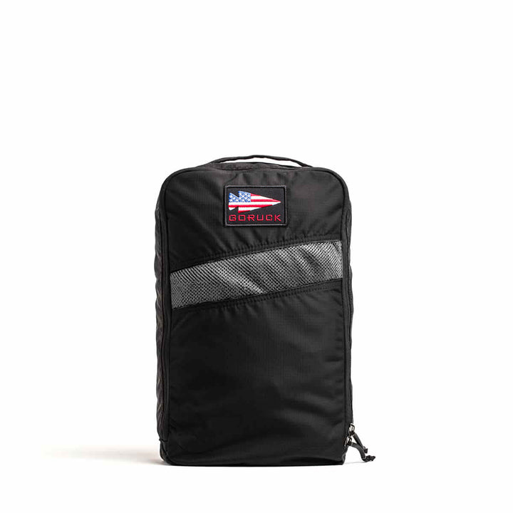 The Shoe Bag - Ripstop ROBIC® is a black zippered shoe packing cube with a mesh panel, made from water-resistant ripstop nylon, and finished with a GORUCK flag patch on the front.