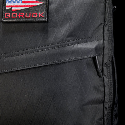 Close-up of the GR1 USA - X-PAC, a black GORUCK rucksack made from durable X-PAC® material, with a USA flag patch on the front.