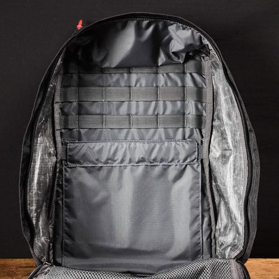 The GR1 USA - Dyneema by GORUCK is displayed against a dark background, revealing an organized interior with multiple compartments and slots for item storage, crafted from durable Dyneema® fabric.