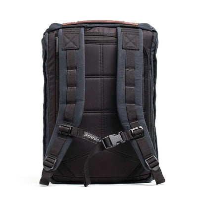 The GORUCK M23 - Waxed Canvas is a black, military-inspired backpack featuring padded shoulder straps and an adjustable chest buckle. Its back panel is designed with thick cushioning for enhanced comfort, while the brand's name is prominently displayed near the buckle area.