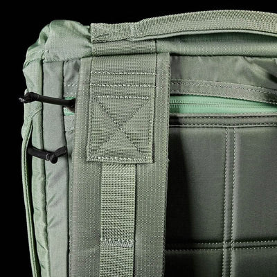 Close-up of a GORUCK M23 - Ripstop ROBIC® rucksack in Seaspray and Speed Tan, highlighting a zippered compartment, two black corded loops, and reinforced stitching. The emphasis is on the durable materials and functional design elements that ensure this field pack's reliability in any situation.