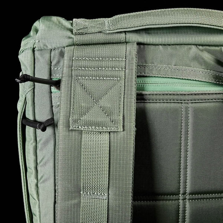 Close-up of a GORUCK M23 - Ripstop ROBIC® rucksack in Seaspray and Speed Tan, highlighting a zippered compartment, two black corded loops, and reinforced stitching. The emphasis is on the durable materials and functional design elements that ensure this field pack's reliability in any situation.