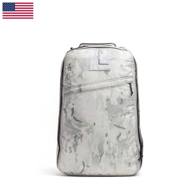A sleek GR1 USA - Cordura backpack by GORUCK, showcased on a white background, embodies its Special Forces inspiration with a gray camouflage design. Created for the GORUCK Challenge, it includes a top handle and multiple zippers. An American flag adorns the top left corner.