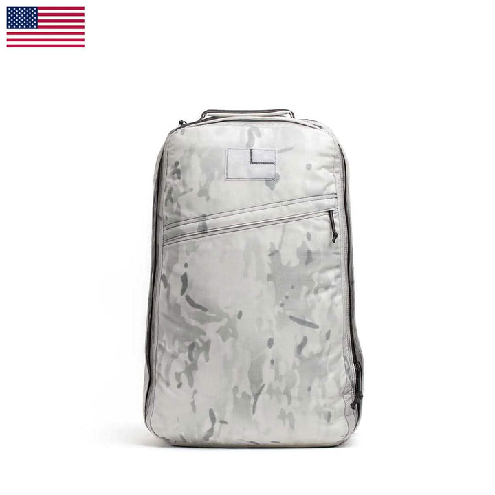 A sleek GR1 USA - Cordura backpack by GORUCK, showcased on a white background, embodies its Special Forces inspiration with a gray camouflage design. Created for the GORUCK Challenge, it includes a top handle and multiple zippers. An American flag adorns the top left corner.