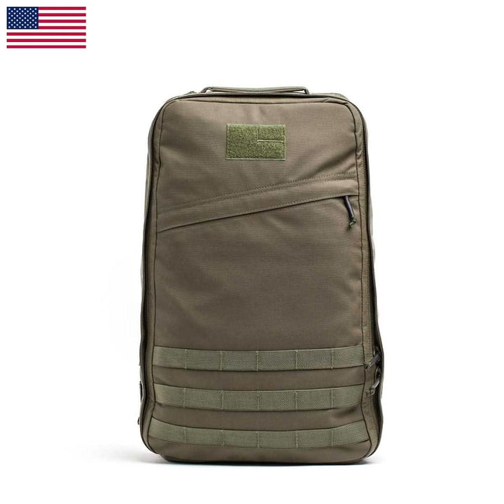 A khaki GR1 USA - Cordura rucksack by GORUCK, featuring MOLLE webbing on the front and a patch area near the top. It stands upright against a white background, with a small American flag in the top left corner, reminiscent of gear used by Special Forces operators.