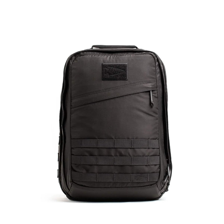 Introducing the GR2 - Ripstop ROBIC® from GORUCK: a sleek, black tactical rucksack with a rectangular design. It features a front zipper pocket, top handle, and multiple rows of MOLLE webbing for attachments. This minimalist travel bag is water-resistant and adorned with a subtle patch on the upper front.