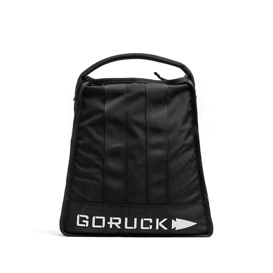A GORUCK Sand Jerry Can in black stands upright, highlighting its minimalist design and vertical stitching with a sturdy handle. Crafted from Special Forces Grade materials, the bag prominently displays the GORUCK logo in bold white letters at the bottom, while a plain white background accentuates its robust structure.