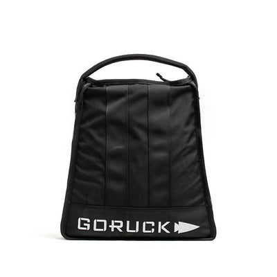 A GORUCK Sand Jerry Can in black stands upright, highlighting its minimalist design and vertical stitching with a sturdy handle. Crafted from Special Forces Grade materials, the bag prominently displays the GORUCK logo in bold white letters at the bottom, while a plain white background accentuates its robust structure.
