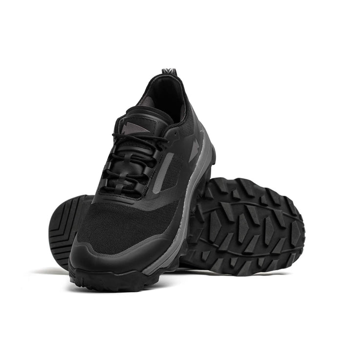 Introducing the Mackall - Black + Forged Iron trail shoes by GORUCK, featuring thick, rugged soles ideal for rucking. One shoe stands upright facing forward, while the other is tilted to showcase its textured sole. Set against a plain white background, these shoes are designed to conquer any terrain or challenge.