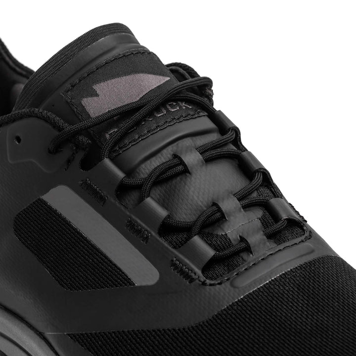 Close-up of the Mackall - Black + Forged Iron trail shoe by GORUCK, showcasing a detailed lacing system on a dark fabric upper. The sneaker boasts sleek, modern design elements with subtle stitching and a textured panel for style and support, making it ideal for Special Forces training.