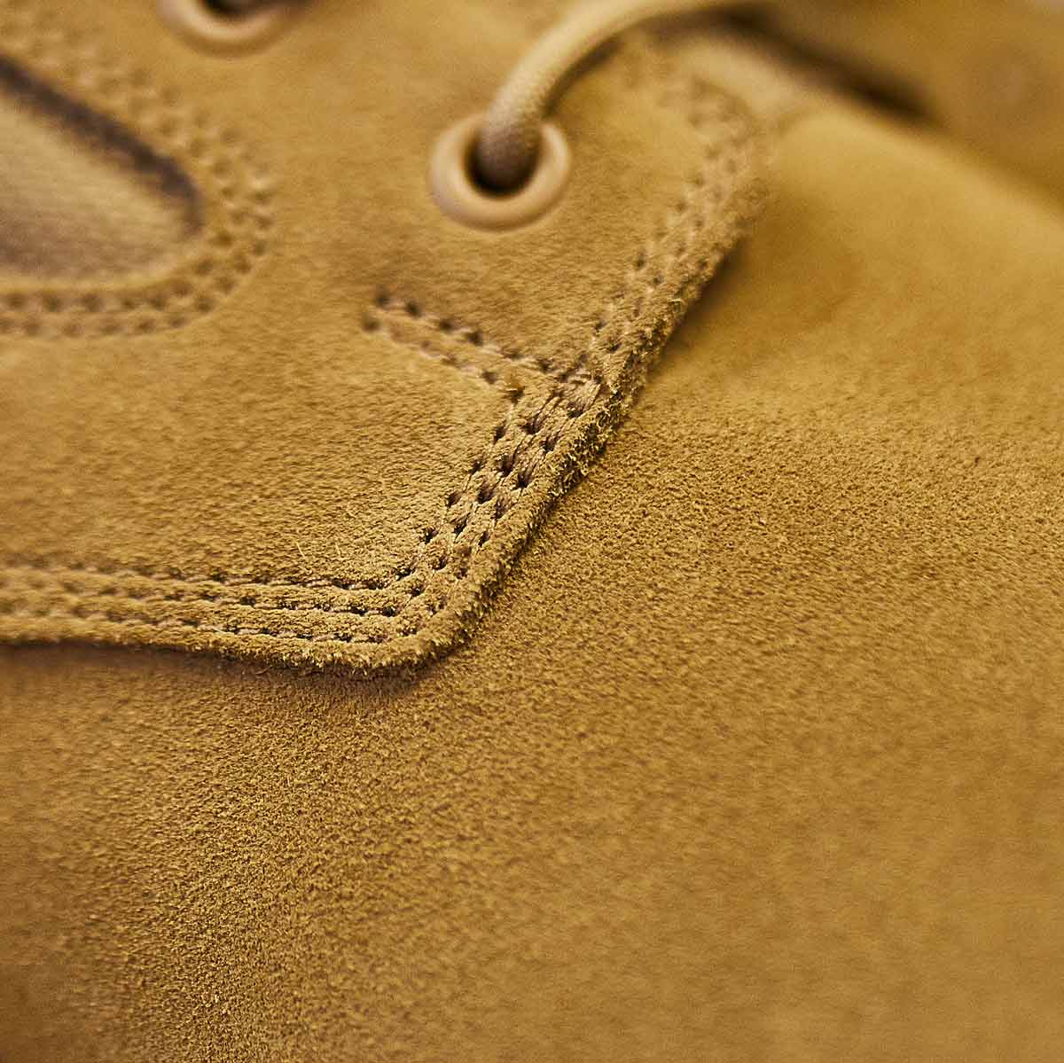 Close-up of the GORUCK MACV-1 High Top in Coyote Suede showcasing its detailed stitching and eyelets with laces. The texture and craftsmanship are prominently displayed, complemented by an all-terrain outsole for enhanced durability.