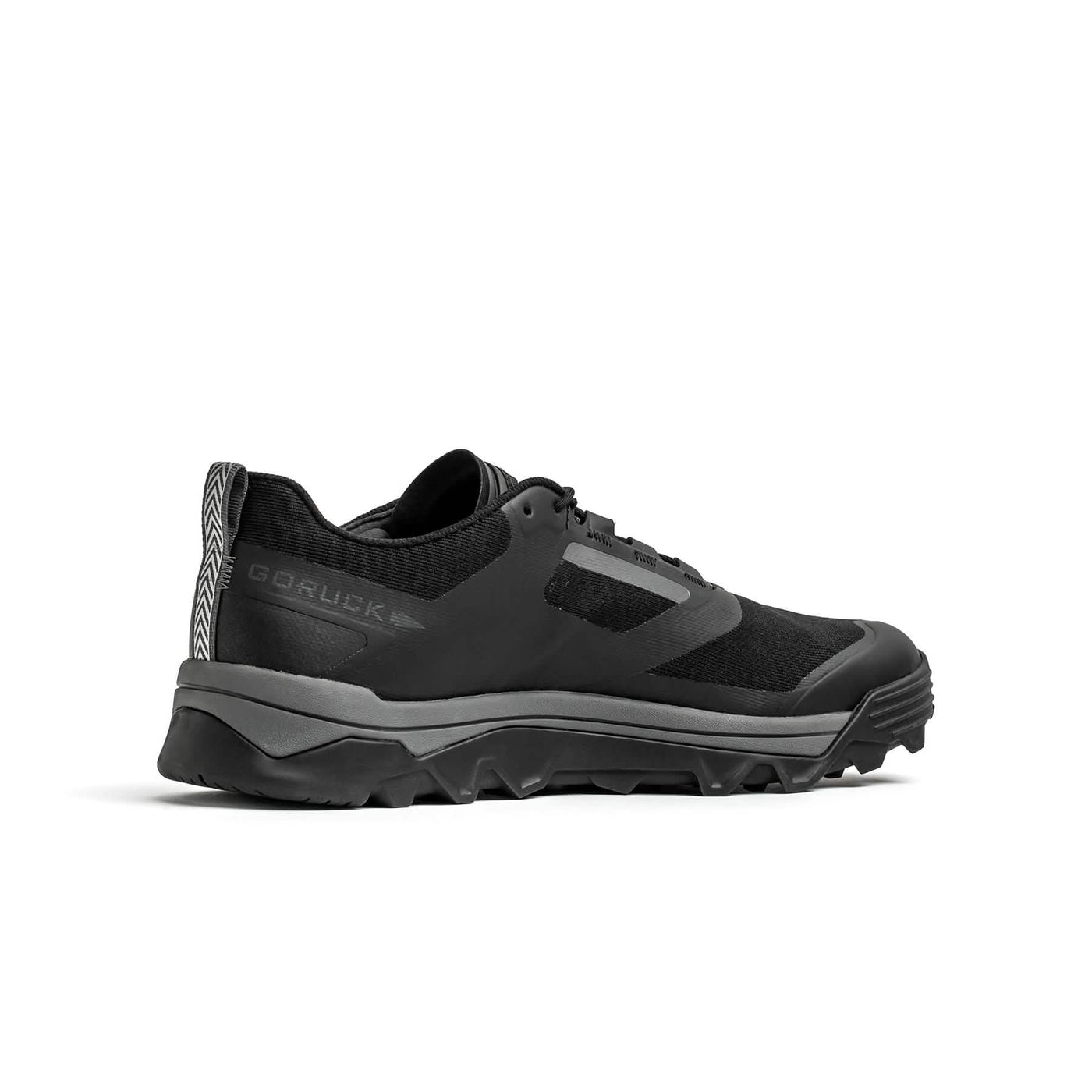 Introducing the Mackall - Black + Forged Iron from GORUCK, a sleek and durable athletic trail shoe designed for peak performance in Special Forces training. Featuring a rugged, textured sole and a synthetic upper, this shoe is perfectly crafted for outdoor activities. The brand's logo is prominently displayed on the side, ensuring both quality and reliability in any terrain.