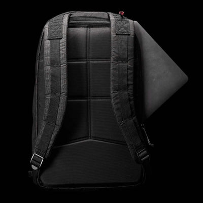 A Bullet Ruck Double Compartment - Dyneema backpack from GORUCK, featuring a black design with padded straps, is displayed on a dark background. A laptop can be seen snugly fitted into the top compartment of the bag. The back panel showcases a grid pattern for enhanced support and comfort, crafted from durable Dyneema material that comes with a lifetime guarantee.