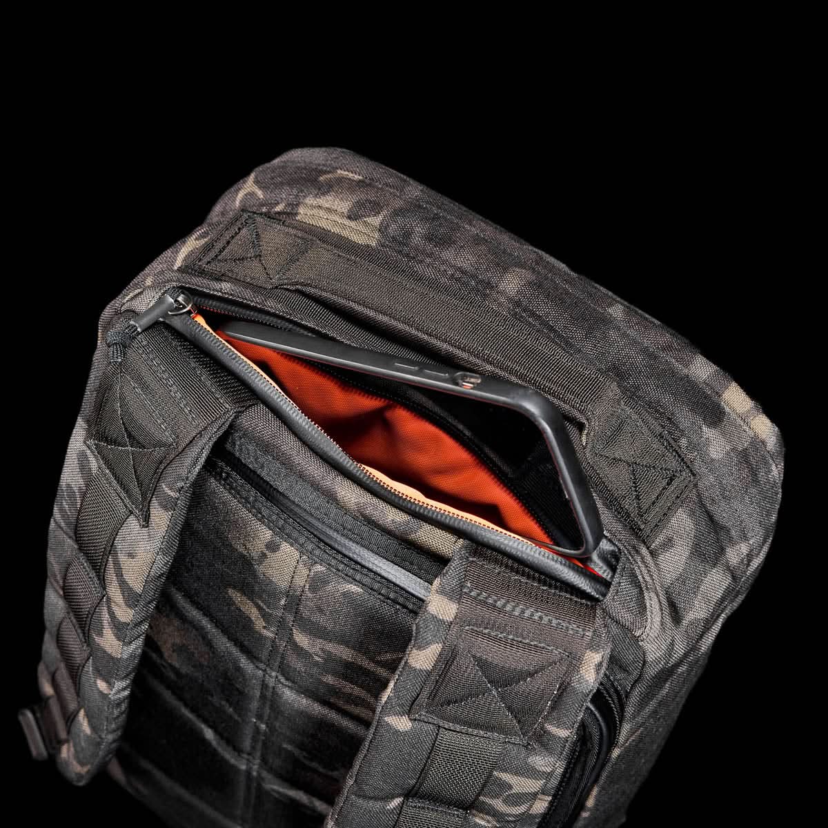 The GR1 USA - Cordura (The Original Ruck) backpack features a camouflage design, made from Special Forces-grade materials, with an open zipper showing an orange interior set against a black background.