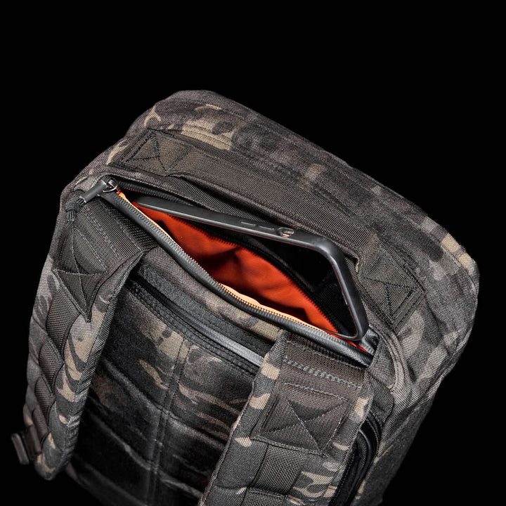 The GR1 USA - Cordura (The Original Ruck) backpack features a camouflage design, made from Special Forces-grade materials, with an open zipper showing an orange interior set against a black background.