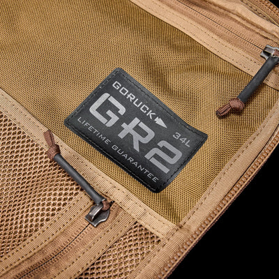 Close-up of a tan GR2 - Ballistic Nylon Cordura ruck featuring a mesh zippered pocket. This carry-on compliant travel bag is perfect for your next adventure.