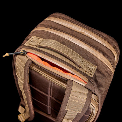 The Bullet Ruck - Ballistic Nylon Cordura - 18L, in brown and tan with an orange interior and bombproof laptop compartment, is displayed from above against a black background.