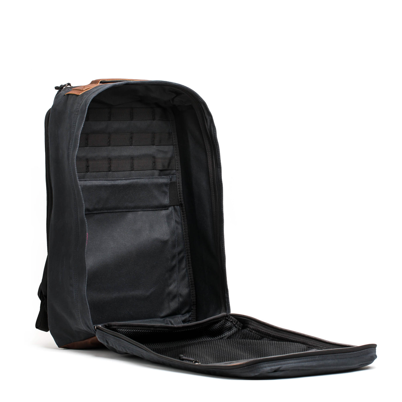 A sleek black GR1 USA - Heritage backpack by GORUCK features a partially open front zipper that reveals multiple compartments and pockets, with an interior design reminiscent of a classic rucksack. It includes a padded laptop compartment and additional sections for organization.