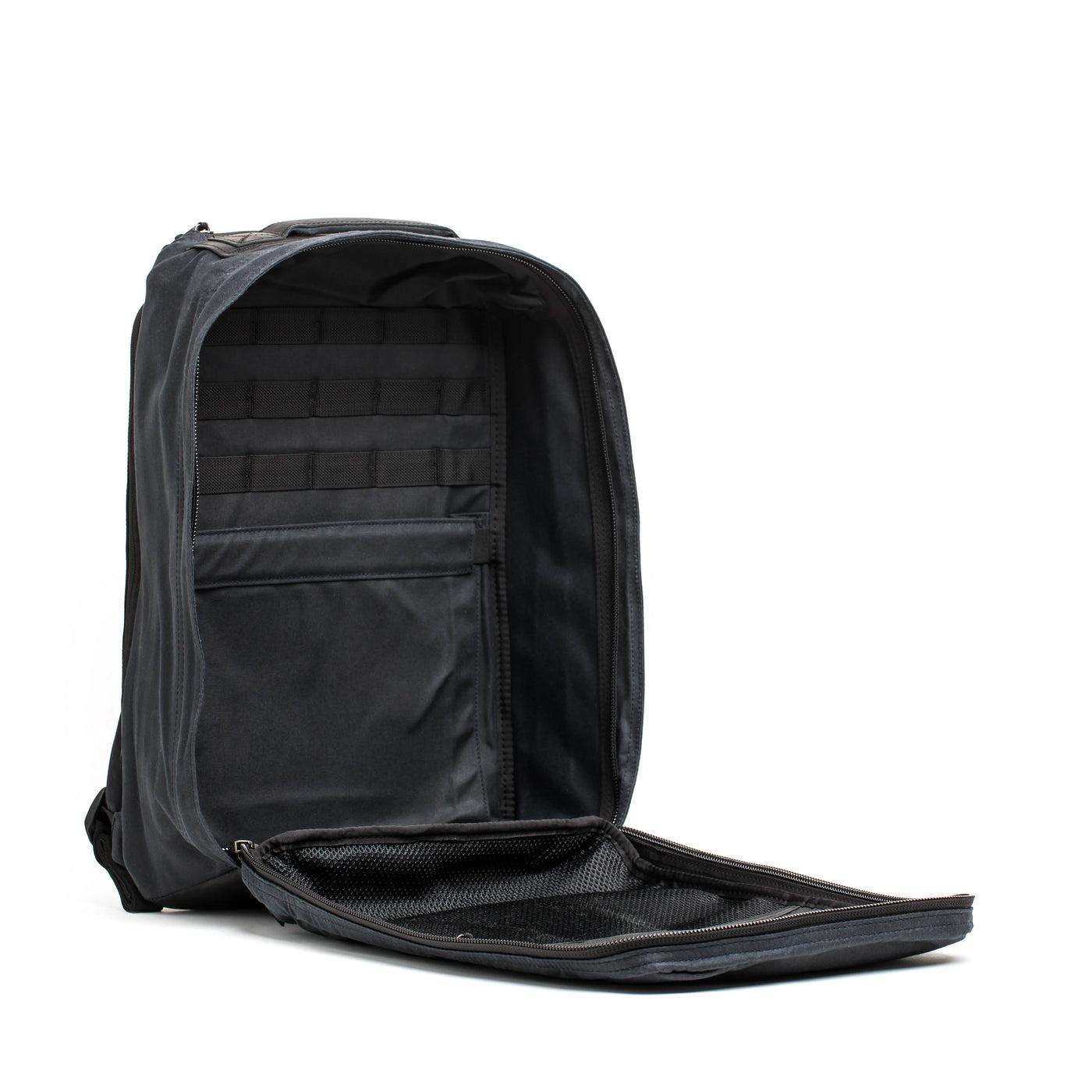 The GR1 USA - Heritage backpack by GORUCK is designed in black waxed duck canvas and features an open main compartment with multiple organizational pockets, including mesh and fabric sections. Its spacious interior accommodates various items, making this rucksack both practical and stylish.