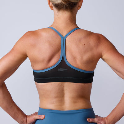 Athletic woman seen from behind wearing the Stealth Bra - ToughFlex in blue and black against a neutral background.