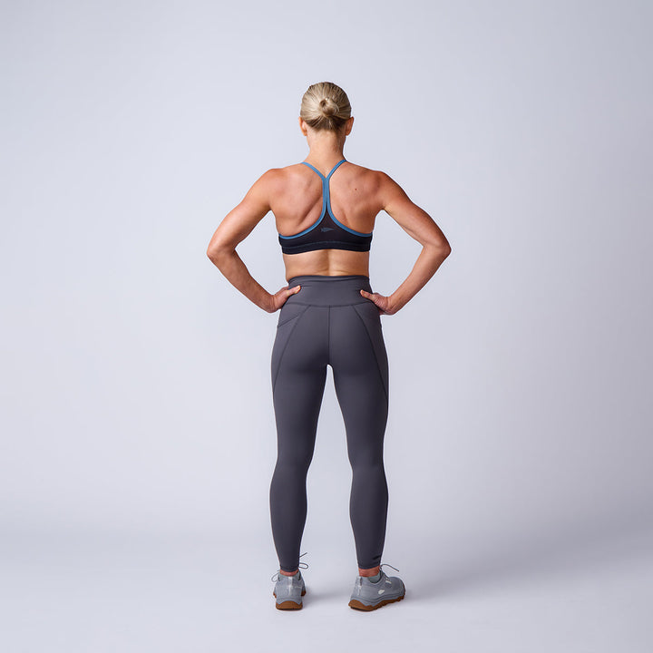 Woman in athletic wear stands with hands on hips, showcasing Women’s Training Leggings Pocket - ToughFlex against a plain light background.
