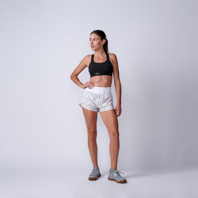 Woman in athletic wear poses against a plain background, wearing a black sports bra and Women’s Training Shorts - ToughStretch, designed for ultimate comfort.