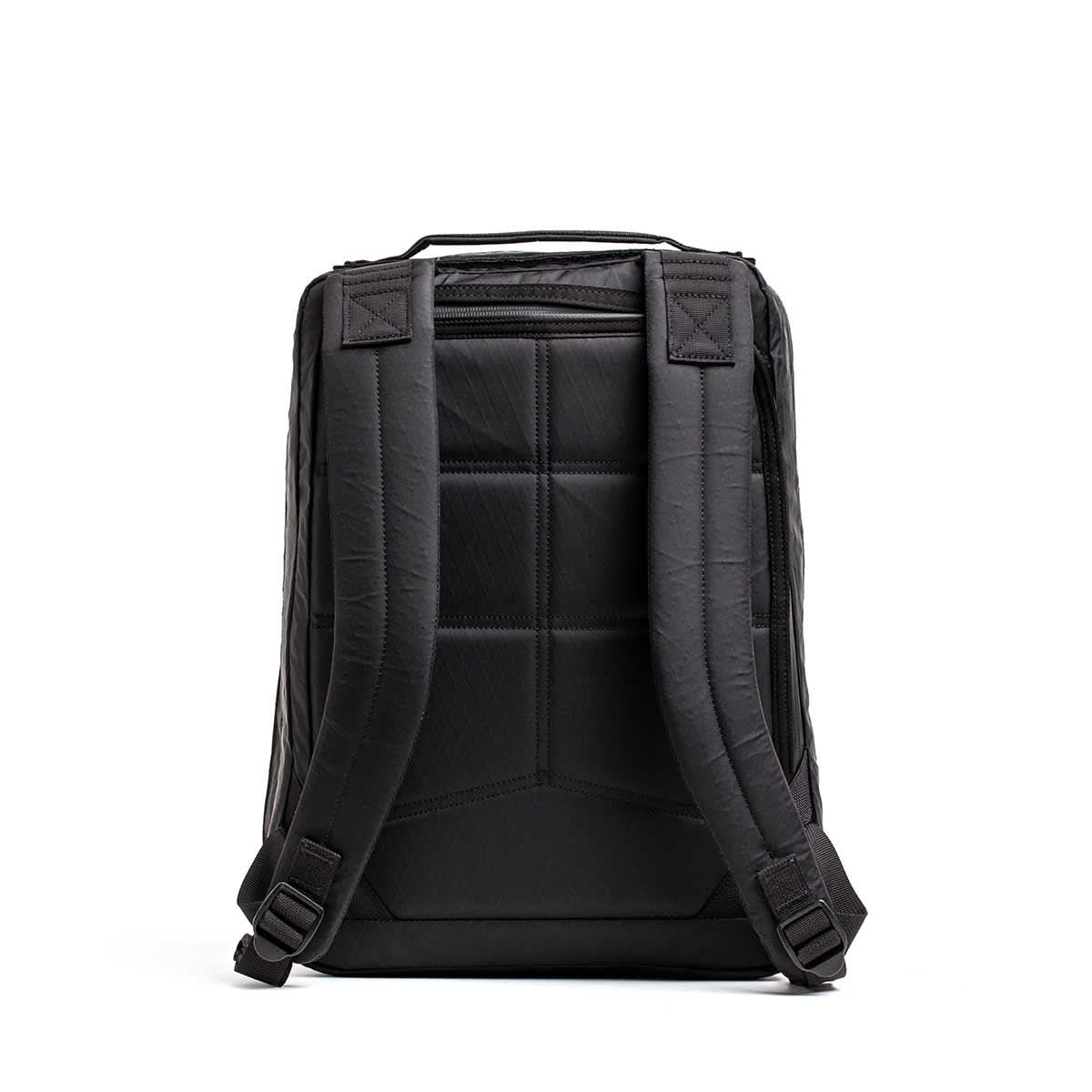 The GR0 - X-PAC is a black, lightweight rucksack shown from the back, featuring padded shoulder straps, a cushioned back panel, and tough waterproof X-Pac material.