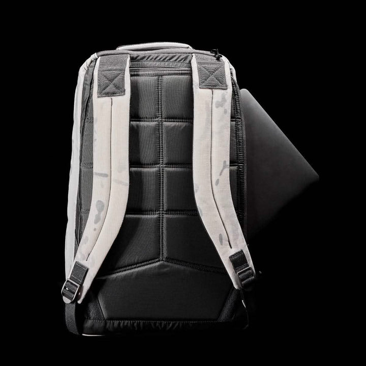 A black and white GR1 USA - Cordura backpack by GORUCK is displayed from the back against a black background. Its padded straps ensure comfort, while the slightly open main compartment reveals a glimpse of its dark interior pocket. Featuring a modern, minimalist design, this backpack is ideal for special forces training.