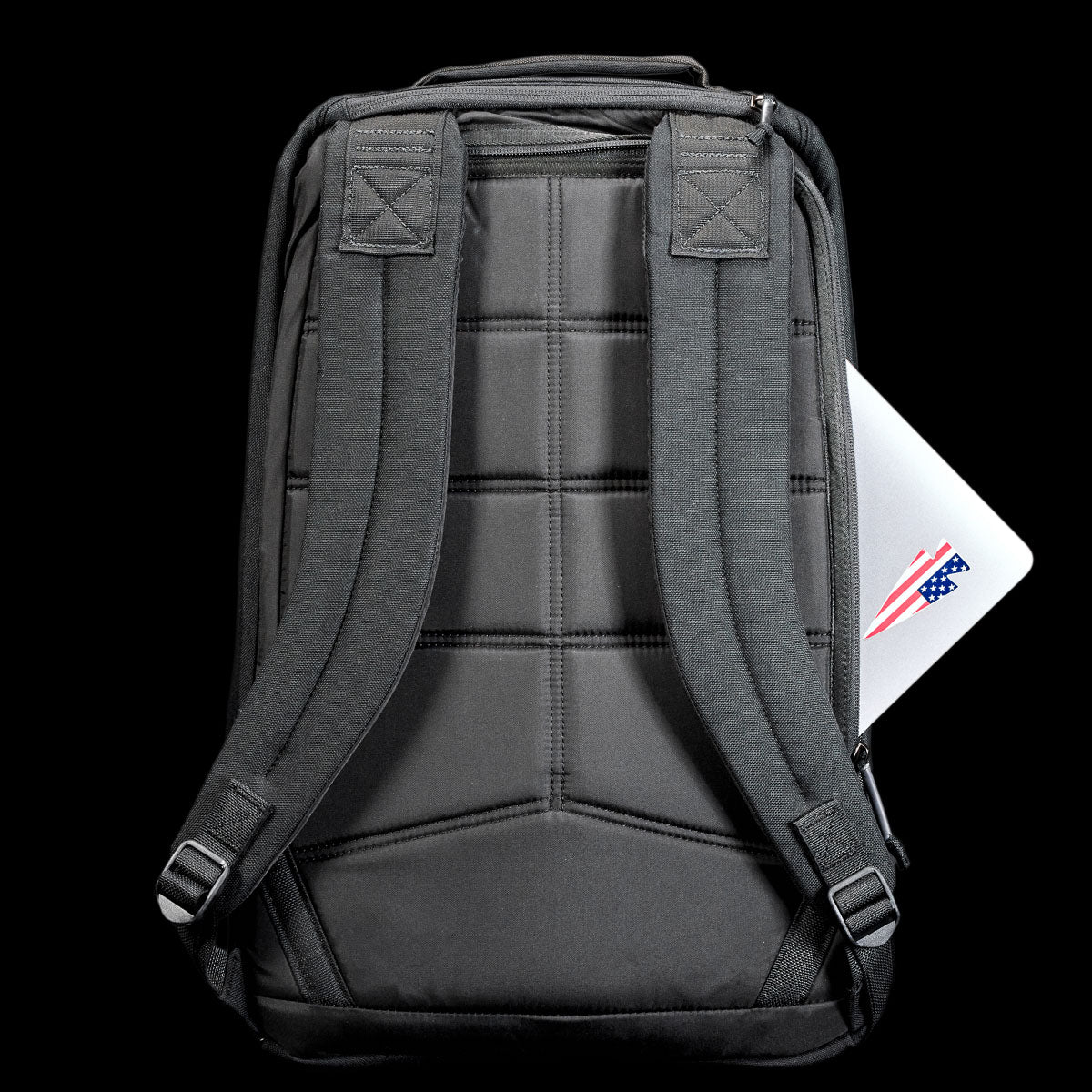 A GR1 Shooter 26L - Built by Scars backpack in gray, featuring durable CORDURA® and padded straps, holds a laptop partially visible in the back pocket against a black background.