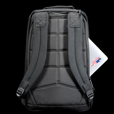 A GR1 Shooter 26L - Built by Scars backpack in gray, featuring durable CORDURA® and padded straps, holds a laptop partially visible in the back pocket against a black background.