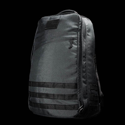 Introducing the GR1 USA - Cordura (The Original Ruck) by GORUCK: a rugged tactical backpack in black, designed with features reminiscent of the GORUCK Challenge. It sports horizontal strap loops on the front and a sleek silhouette, complete with a small patch at the top that enhances its Special Forces allure. The solid black background accentuates the texture and intricate details of the bag.