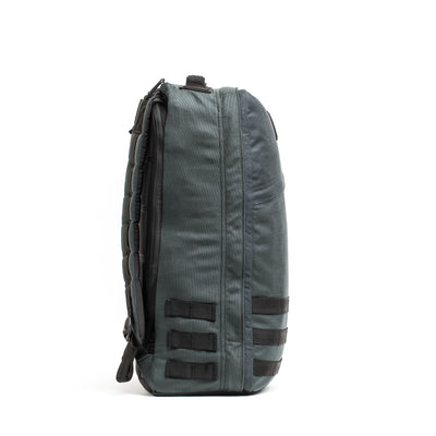Here is a rewritten version of the sentence using the product data:

Side view of a dark gray GORUCK GR1 USA - Cordura backpack with padded straps, inspired by Special Forces requirements. It includes multiple compartments and black attachment loops on the side, standing upright against a plain white background.