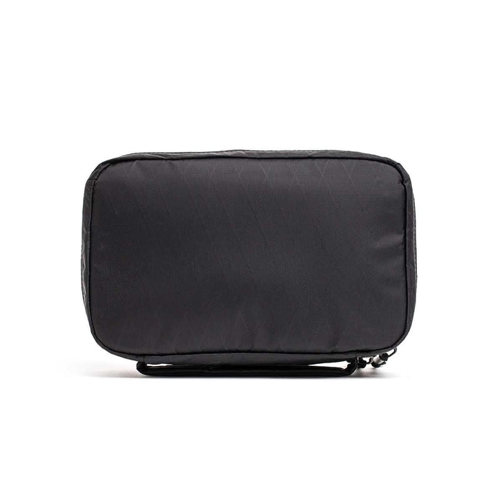 The GR1 Field Pocket - X-PAC is a rectangular black travel pouch with AquaGuard zippers, shown standing upright on a white background—ideal for organizing electronics.
