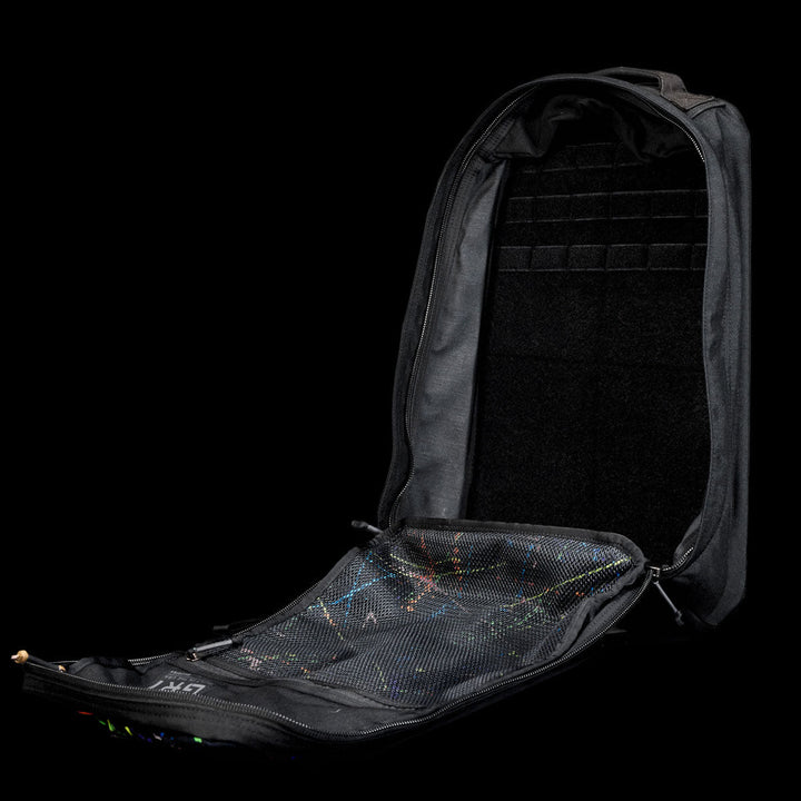 A black GR1 Shooter 26L - Built by Scars backpack, unzipped and open, made from Special Forces Grade CORDURA®, shows a mesh pocket inside the front flap.