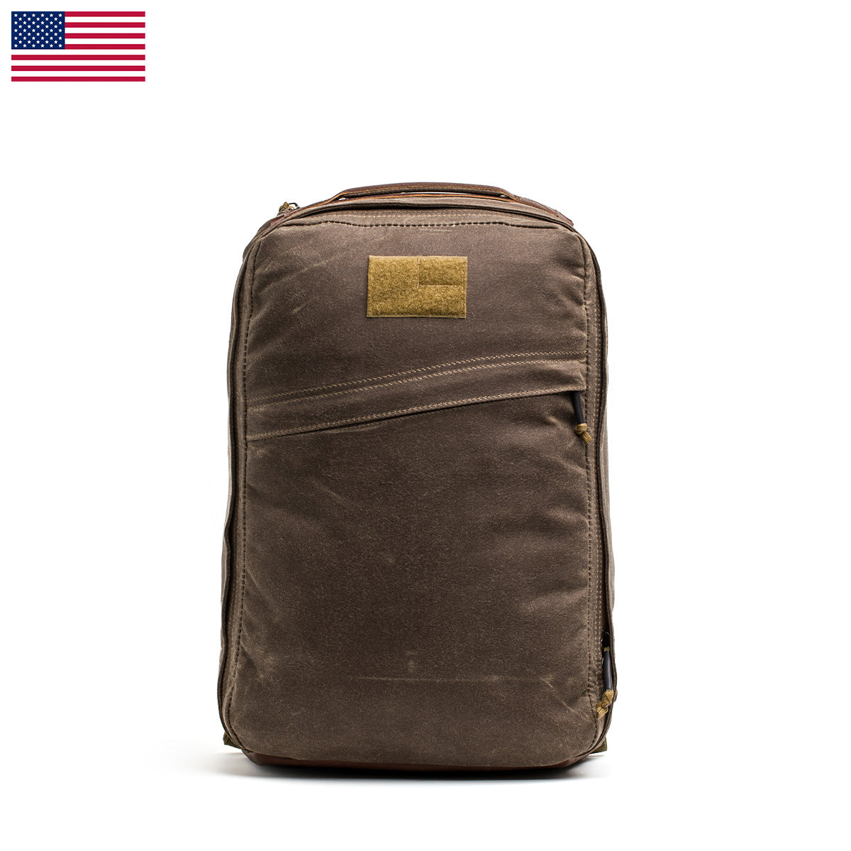 The GR1 USA - Heritage Waxed Canvas is a durable backpack made from waxed duck canvas, featuring a tan patch and a small American flag in the top left corner.