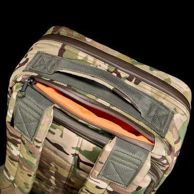 Close-up of the GR1 USA - X-PAC lightweight camouflage backpack featuring an open top with an orange interior against a black background.