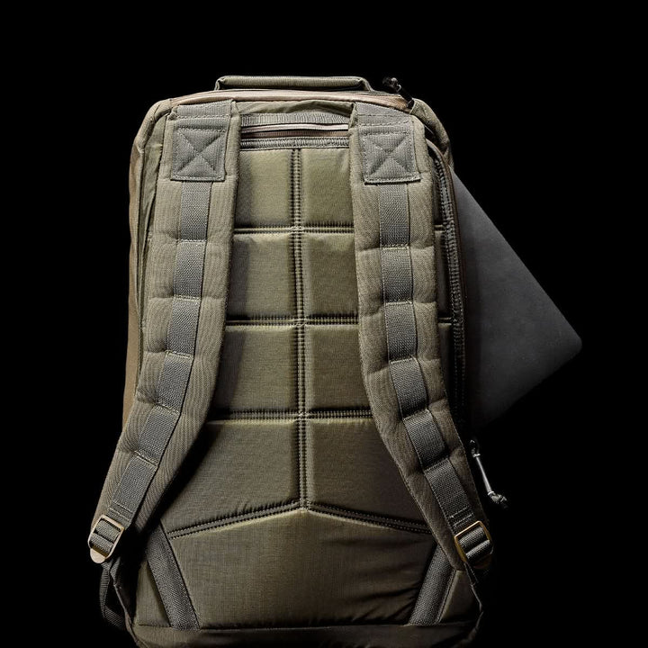 The GR1 USA - Cordura (The Original Ruck) in olive green, crafted from Special Forces-grade materials, showcases padded straps. On a black background, it’s partially open with a laptop visible.