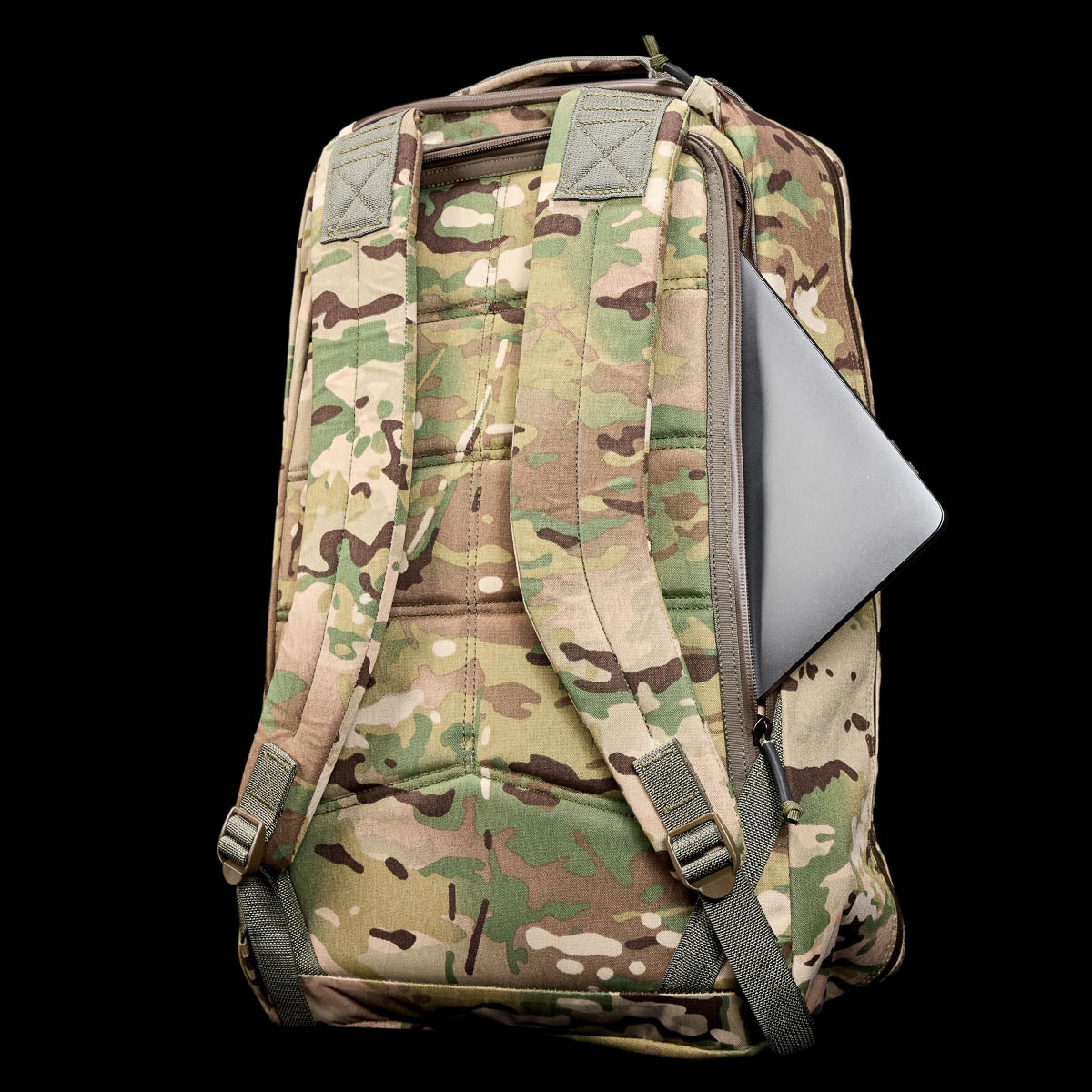 The GR1 USA - X-PAC camouflage rucksack, made from durable material, showcases a laptop peeking from its side pocket against a sleek black background.