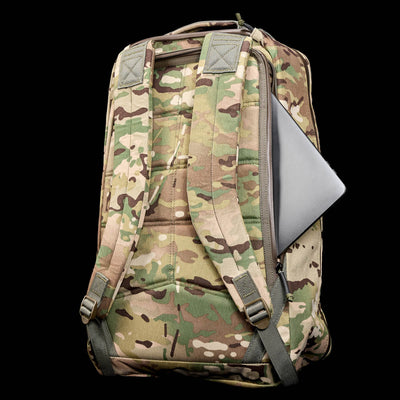 The GR1 USA - X-PAC camouflage rucksack, made from durable material, showcases a laptop peeking from its side pocket against a sleek black background.