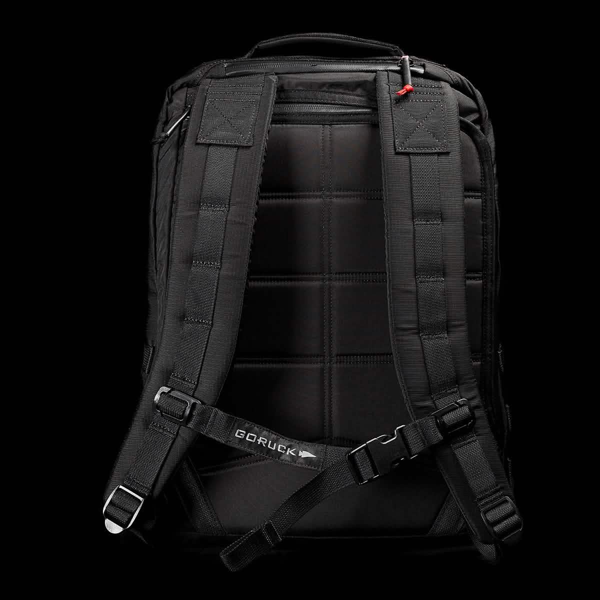 Displayed against a dark background is the GR2 - Ripstop ROBIC® rucksack in black, complete with padded shoulder straps and a chest strap. The back panel includes quilted padding for added comfort, while the GORUCK brand name is visible on the chest strap. This water-resistant travel bag combines style and practicality, making it an ideal companion for any journey.