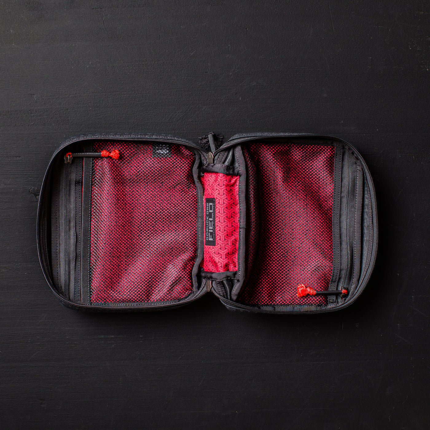 An open GR2 Field Pocket - GRXC2 Samurai 2.0, crafted from JPXDP fabric in black and red with mesh pockets and a zippered design, lies on a black surface.