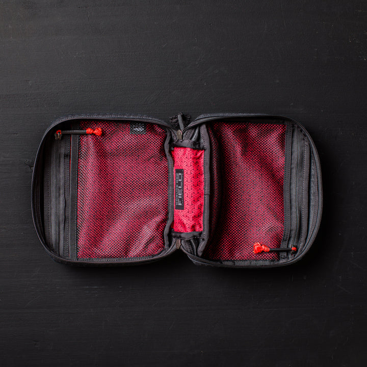 An open GR2 Field Pocket - GRXC2 Samurai 2.0, crafted from JPXDP fabric in black and red with mesh pockets and a zippered design, lies on a black surface.