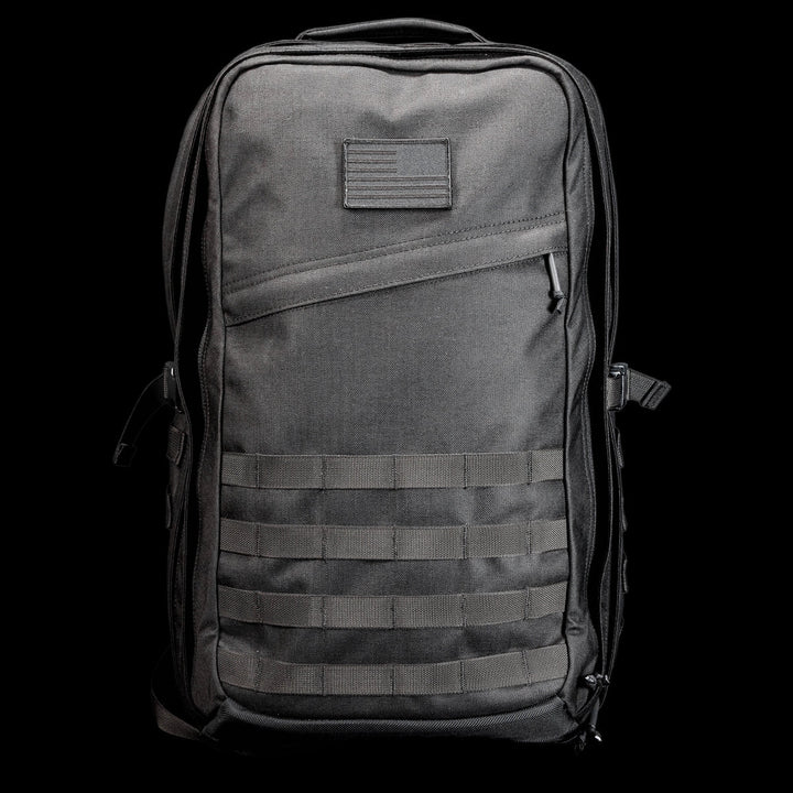 The GR2 USA Throwback is a black tactical travel backpack, crafted from rugged 1000D Cordura with MOLLE webbing and a small front patch, shown against a black background.