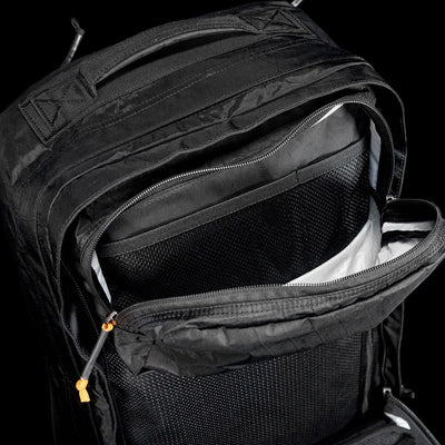 The GR2 X-PAC backpack in black features AquaGuard zippers, a mesh pocket, and a zippered compartment, displayed against a black background.