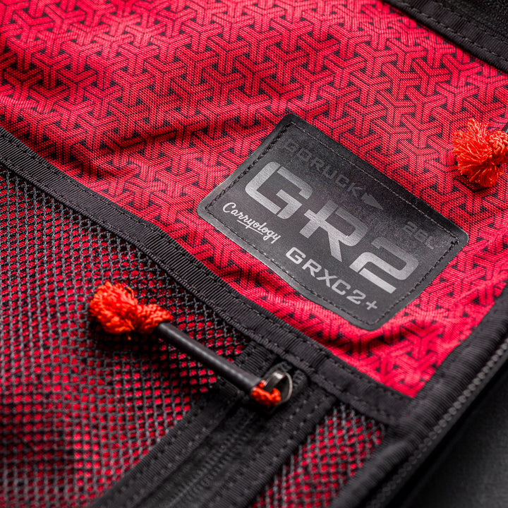 Close-up of a red fabric backpack interior with black mesh pocket and "GR2" patch, from the GR2 x Carryology - GRXC2 Samurai 2.0 collaboration.