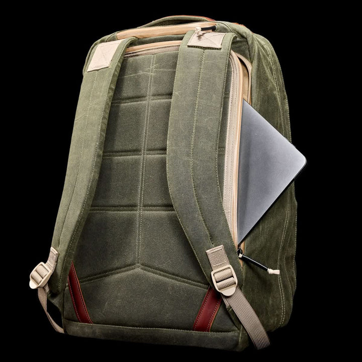 GR2 - Waxed Canvas travel ruck in green features padded straps and a side zipper pocket with a partially visible laptop, crafted from durable duck canvas, shown on a black background.