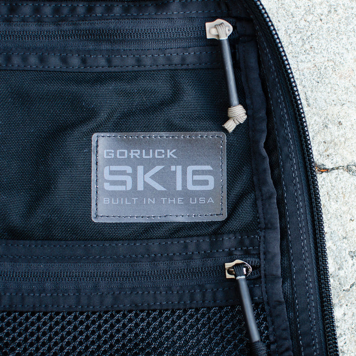 Close-up of a GR0 USA Slick - Ballistic Nylon Cordura tag on a black mesh pocket with zippers, made in the USA from rugged Cordura for top-tier durability.