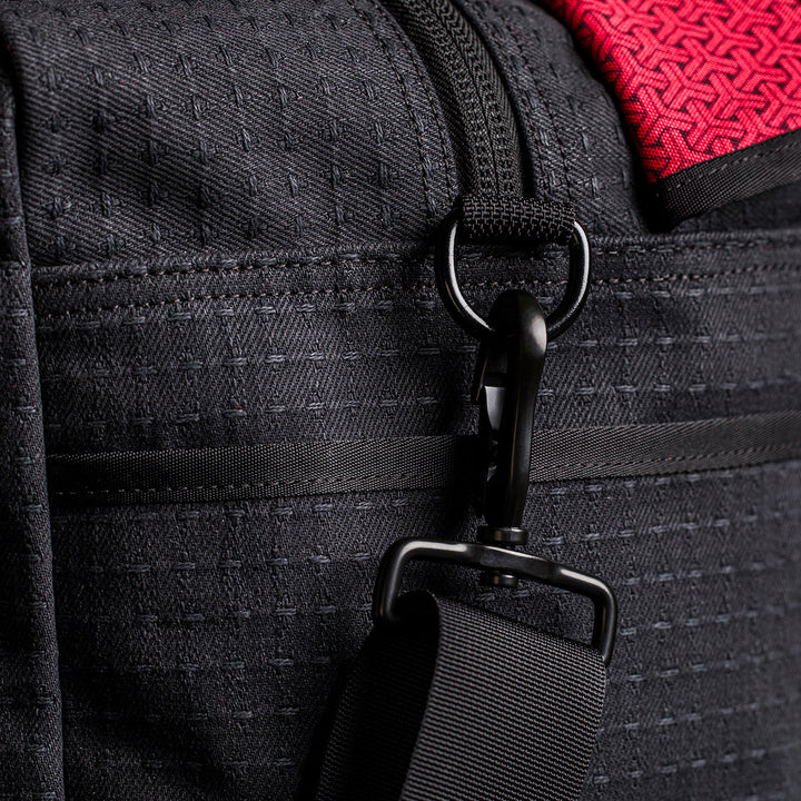 Close-up of the Kit Bag x Carryology - GRXC2 Samurai 2.0 in black technical fabric, designed with a detachable shoulder strap and a red accent at the top.