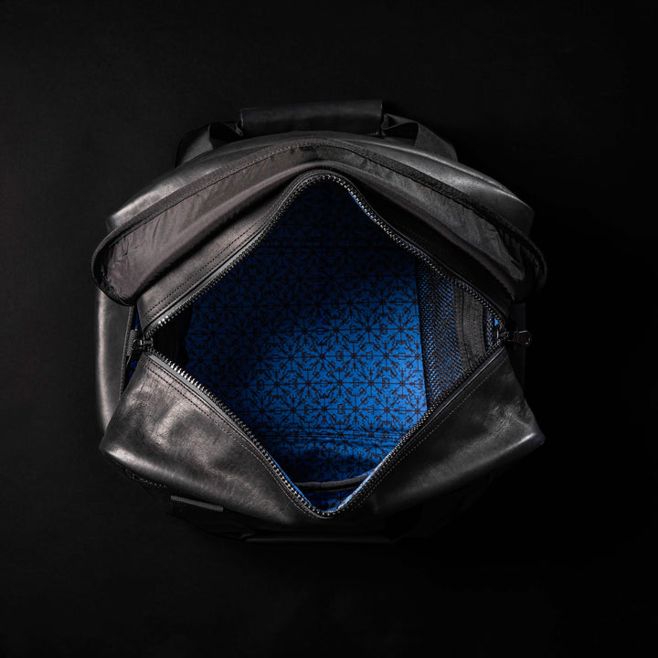 Explore the GORUCK Kit Bag x Carryology - Berserker Viking, a black leather bag with a distinct blue patterned interior, set against a dark backdrop.