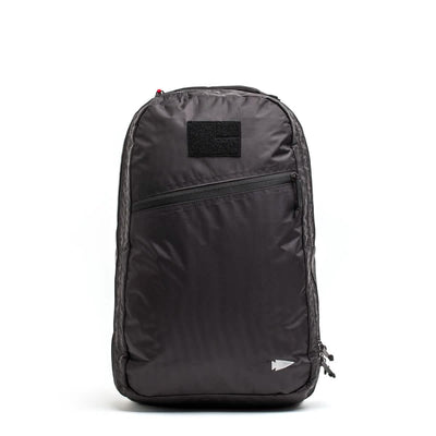 The GORUCK Bullet Ruck Double Compartment in black showcases a minimalist design with a front zippered pocket and a small square patch above it. Made from durable Dyneema, it features a subtle arrow emblem near the bottom right and comes with our Lifetime Guarantee for peace of mind.